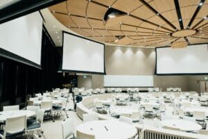 Image Title: Immersive Event Design Alt Text: A photo of an empty conference room with projector screens. Source: https://unsplash.com/photos/photo-of-empty-room-with-projector-screen-Q_KdjKxntH8