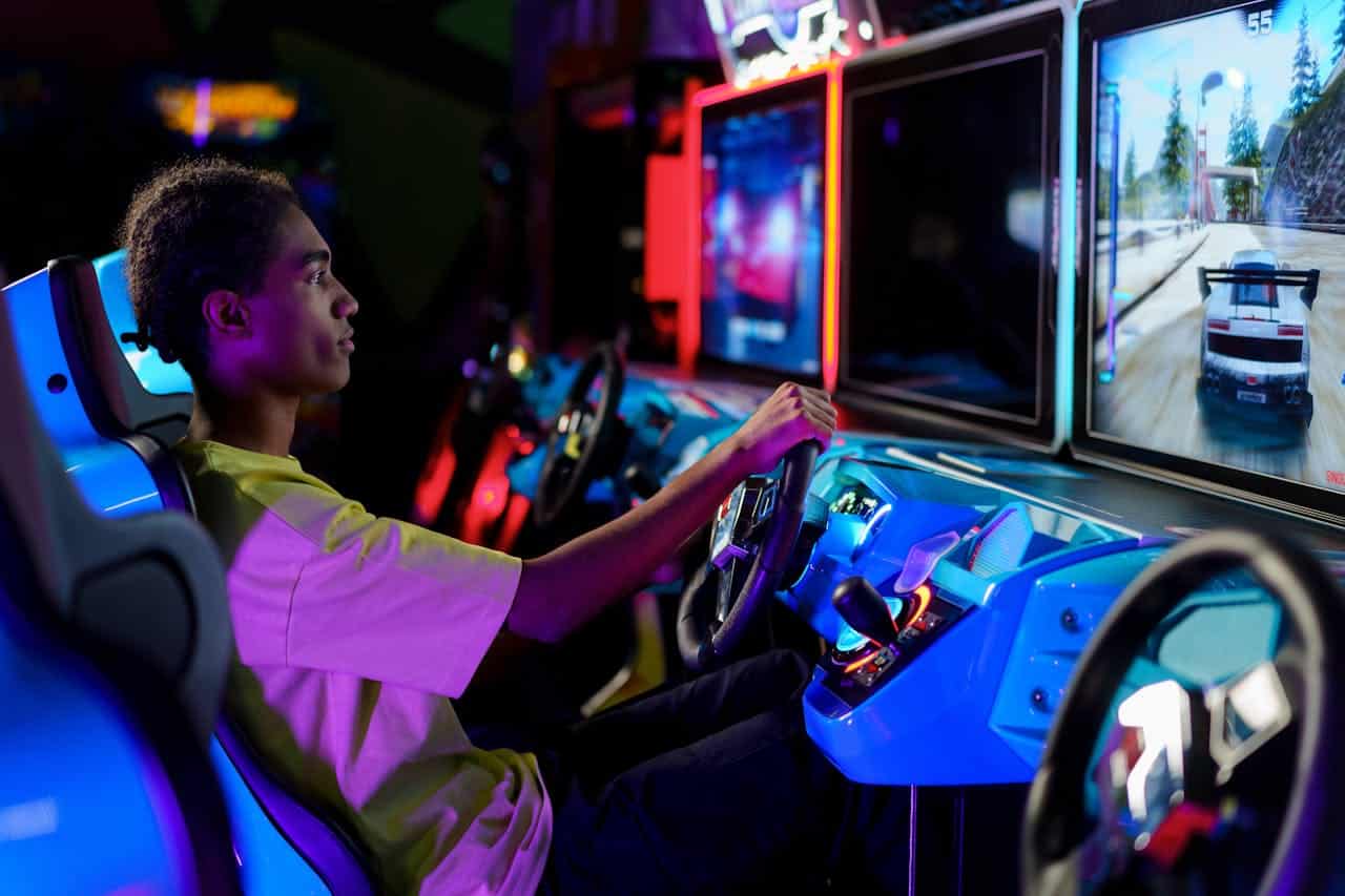 Photo by cottonbro studio: https://www.pexels.com/photo/man-playing-car-racing-arcade-machine-5767684/ -- event arcade